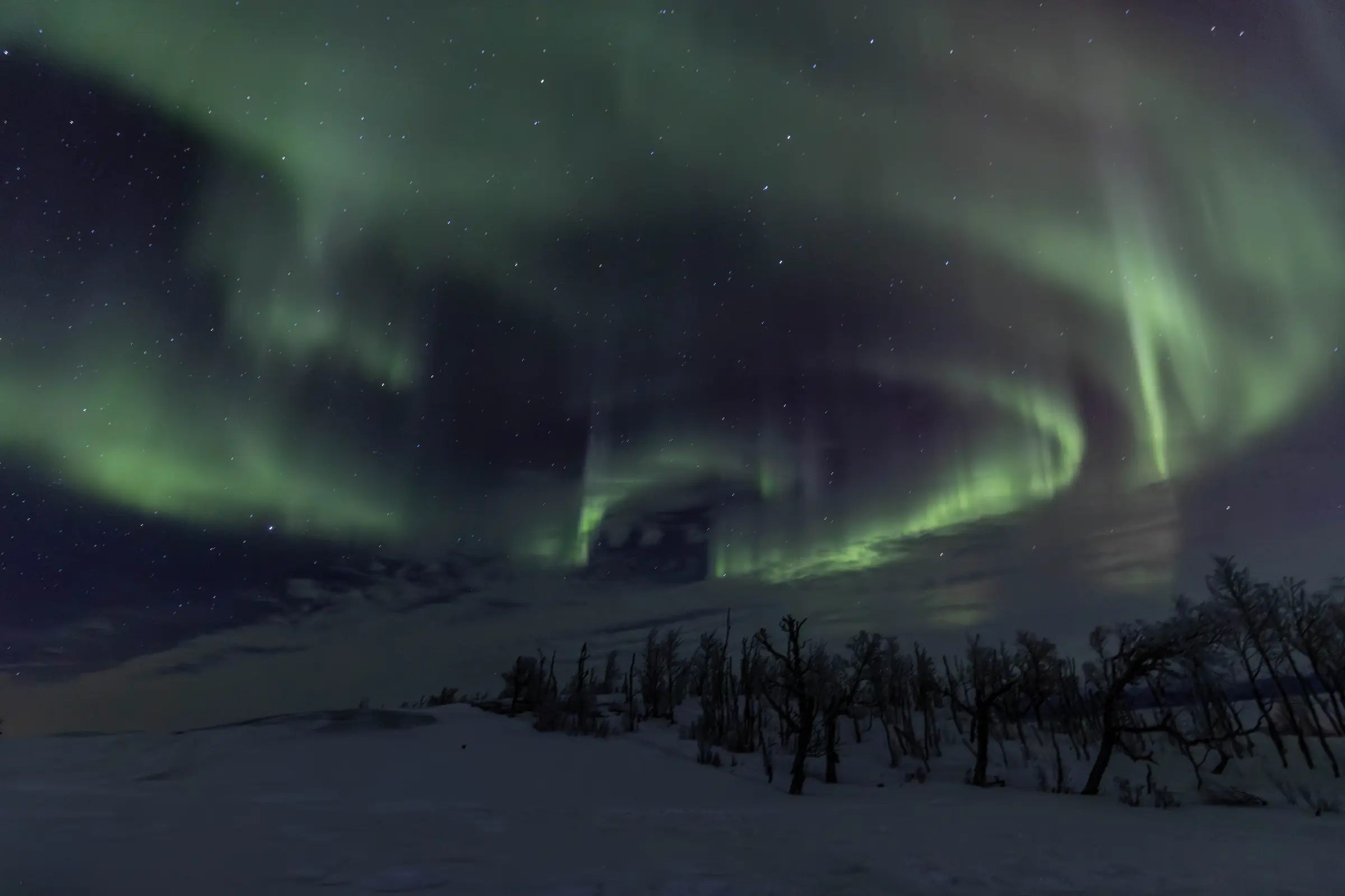 Green northern lights over a snowy valley